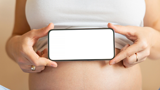 Pregnancy mockup display. Pregnant woman holding smartphone. Mobile pregnancy online maternity application mock up. Concept maternity, pregnancy, childbirth