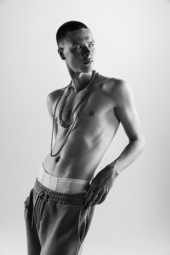 Portrait of handsome young man posing shirtless. Black and white photography. Textured body shape. Male accessories. Body art. Concept of fashion, style, body aesthetics, beauty, men's health