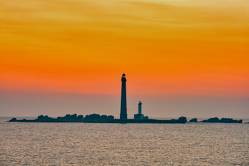 View of a beautiful sunset next to a lighthouse on the Normandy coast in France.