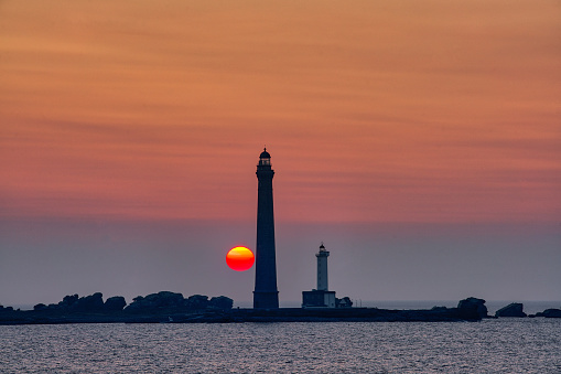 View of a beautiful sunset next to a lighthouse on the Normandy coast in France.