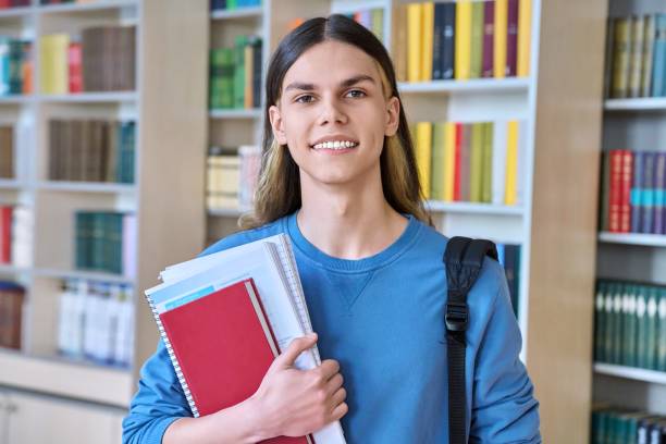 istock Portrait of a student guy with textbooks looking at camera in college library 1401491218