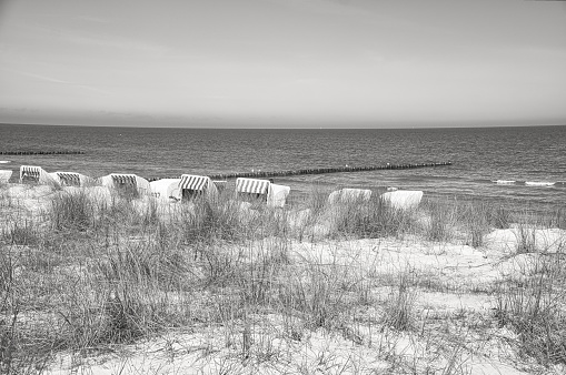 Beach chairs in black and white on the beach of Zingst on the Baltic Sea. Vacation with sunshine and sea. Taken behind the dunes.