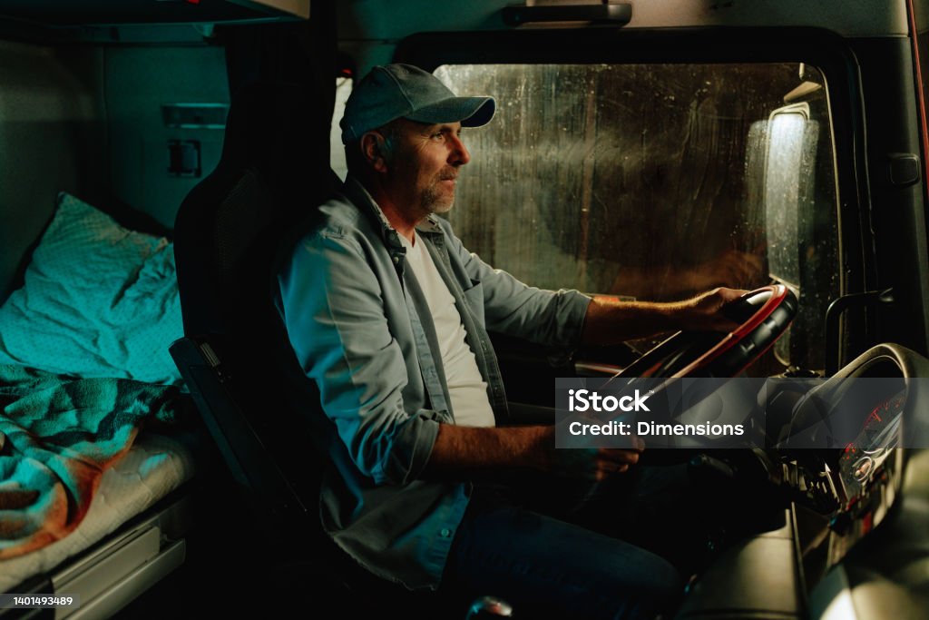 Truck driver driving long distance at night A truck driver is driving a long distance load during his nightshift Truck Driver Stock Photo