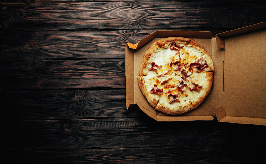 Pizza in a box on wooden background top view