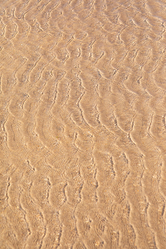 A shot of the sea rippling over sand at Beadnell beach, North East England.