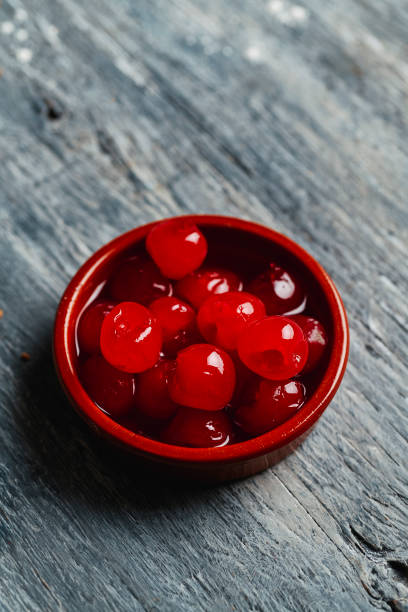 some maraschino cherries in a bowl some maraschino cherries in a brown earthenware bowl, on a gray rustic wooden table maraschino cherry stock pictures, royalty-free photos & images
