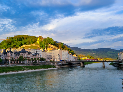 The river Salzach in Salzburg, Austria on a bright spring morning.  In the background are the buildings on the side of the river lit by late afternoon spring sunshine.