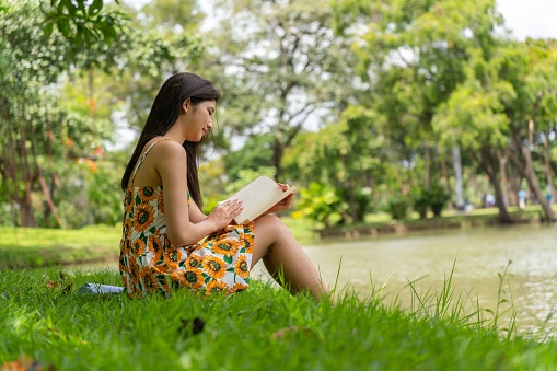 Photograph of a young asian lady chilling and relaxing in a park by doing different activities.
