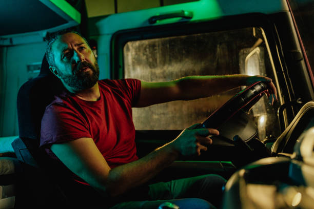 istock Truck driver looking in sideview mirror at nightshift 1401497077