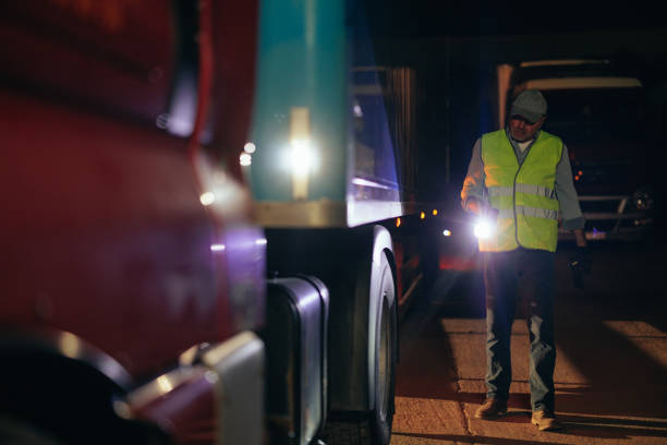 Truck driver with flashlight checking up truck before drive