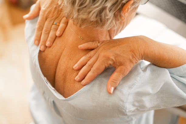 mulher idosa massageando a dor em seu pescoço - backache massaging pain back - fotografias e filmes do acervo