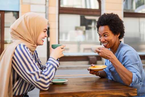 Woman wearing hijab chatting during coffee break with her friend