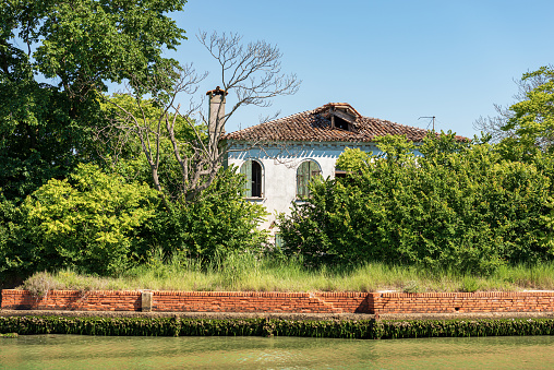 Abandoned and broken house in the Venice lagoon, partially hidden by vegetation. Venice, UNESCO world heritage site, Veneto, Italy, Europe.