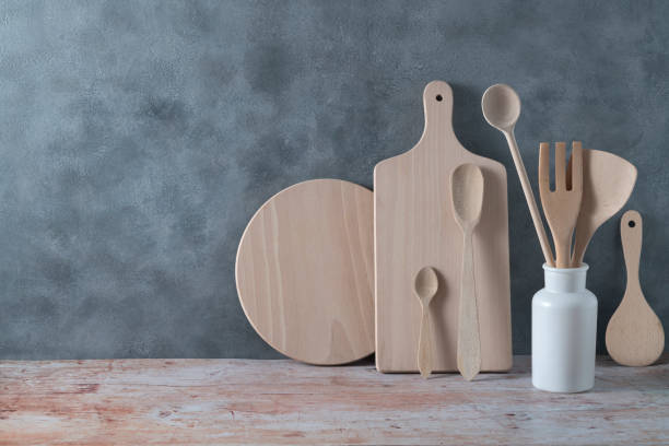 menaje de cocina moderno en color madera clara con cucharón, tablas de cortar y utensilios de cocina sobre gris - tienda de artículos de cocina fotografías e imágenes de stock