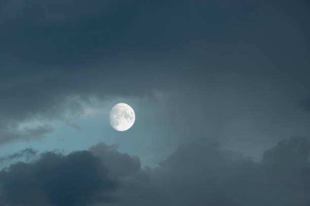 istock Cloudy night with the moon appearing from behind the clouds. 1401503081