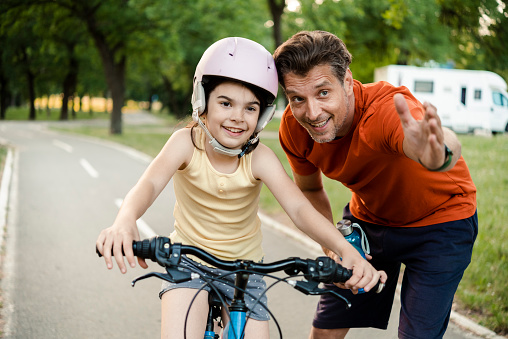 Little girl learning how to ride a bicycle with her father at the park