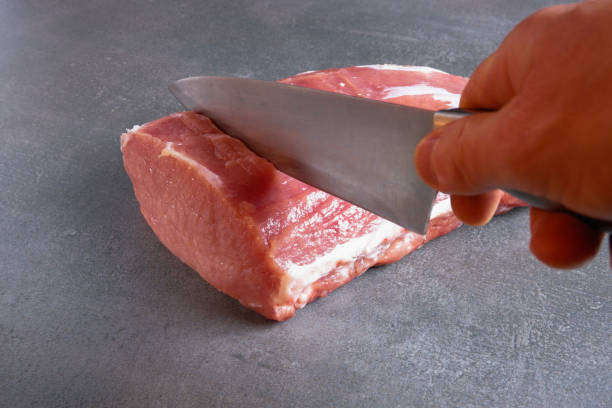 istock The chef is cutting fresh raw meat into steaks. Close-up on a gray background. 1401507471