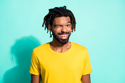Photo portrait of winking black skin man smiling isolated on vivid cyan colored background