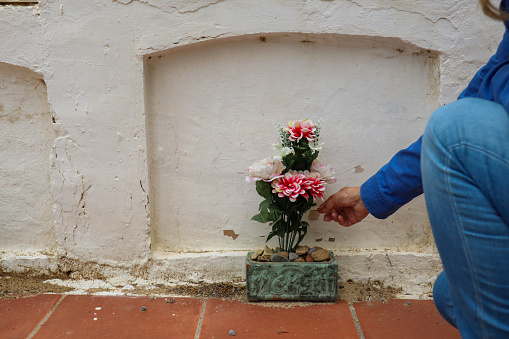 A woman hand with a bouquet of flowers in a cemetery in Spain