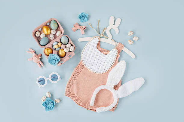 istock Cute baby costume Easter bunny. Knitted bodysuit with fluffy  bunny ears, Easter eggs and candy on blue background. Holiday concept. Flat lay, top view 1401511409