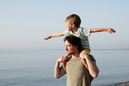 Young father with his son having fun together near the sea. Father’s Day