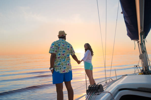 Date of guy and girl on a yacht. Journey around the world on a yacht. Love story. Honeymoon trip on a sailing yacht. Yacht at sunset. Date of guy and girl on a yacht. Trip around the world. sailing couple stock pictures, royalty-free photos & images