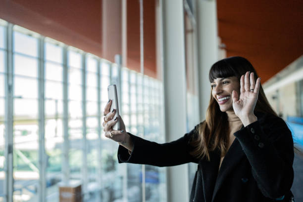 istock Young woman doing a video call using smartphone in an airport 1401521380