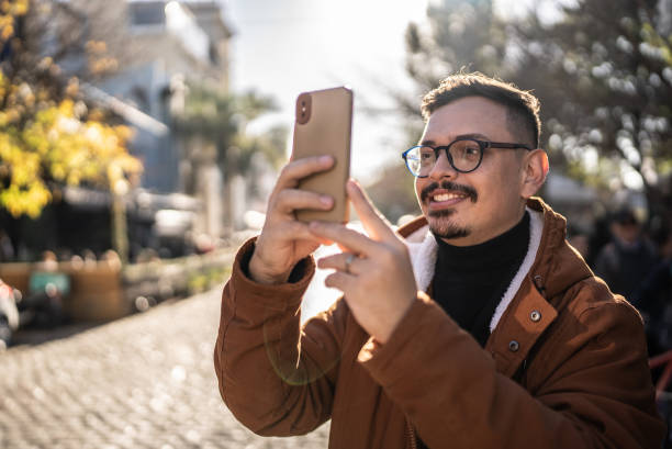 istock Happy young man taking photos using smartphone outdoors 1401521431