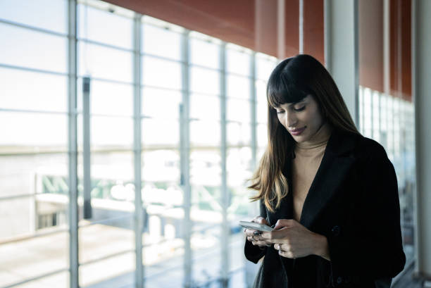 istock Young woman using smartphone in an airport 1401521514