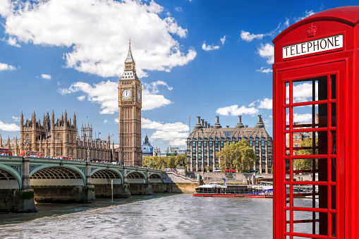 A line of classic vintage (1930's) public telephone boxes (kiosks) standing against painted ornate Victorian (19th century) iron railings in the City of London