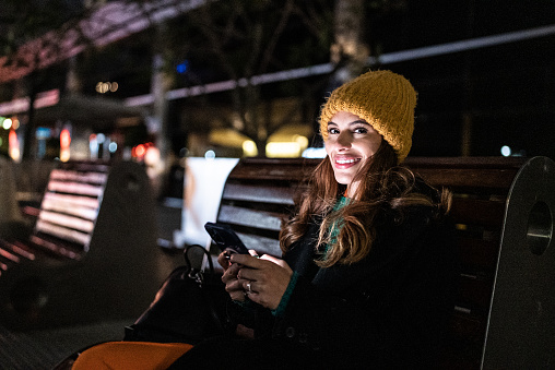 Portrait of a young woman using the mobile phone in the street