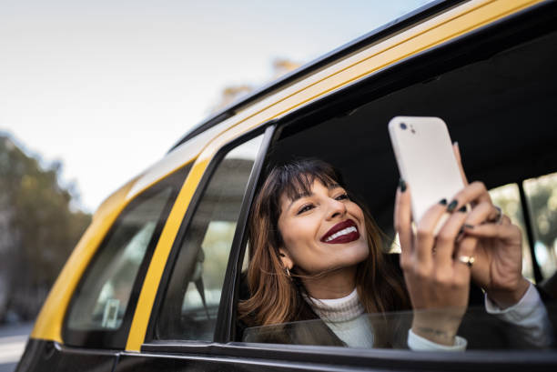 joven filmando o fotografiando la vista en el teléfono móvil en un taxi - taxi buenos aires people city fotografías e imágenes de stock