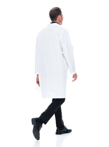 Caucasian male doctor walking in front of white background wearing lab coat stock photo