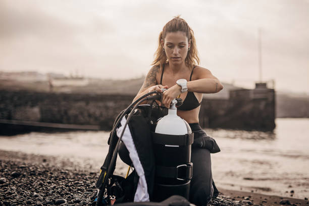 ウェットスーツの女性ダイバーが水に入る前に酸素タンクを準備する - oxygen tank underwater diving diving wetsuit ストックフォトと画像