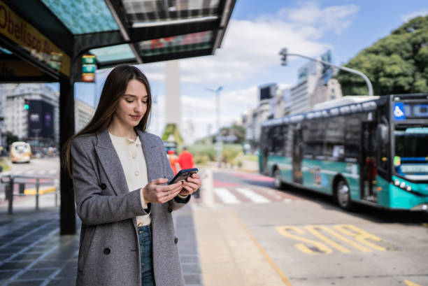 istock Young woman using the mobile phone at the bus stop 1401528109