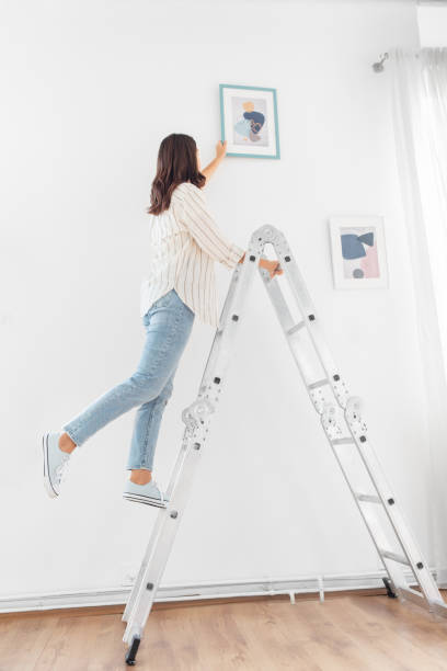 istock woman on ladder decorating home with art 1401528681
