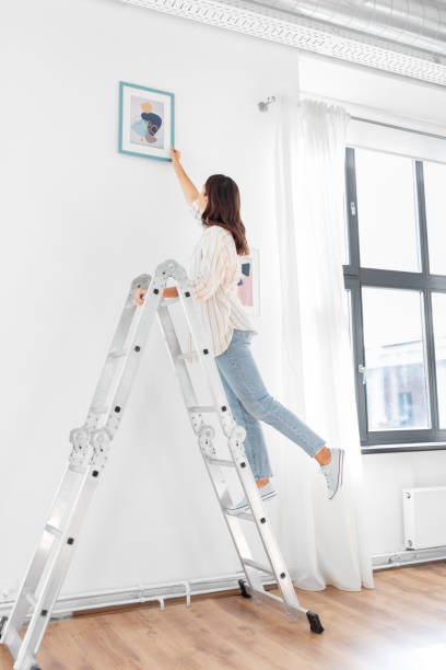 istock woman on ladder decorating home with art 1401529088