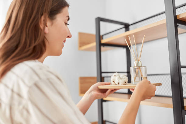 woman placing aroma reed diffuser to shelf home home improvement, decoration and people concept - happy smiling woman placing aroma reed diffuser to shelf home diffuser stock pictures, royalty-free photos & images