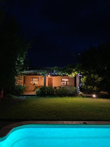 Shed lit up at Night with Pool and Palm Tree