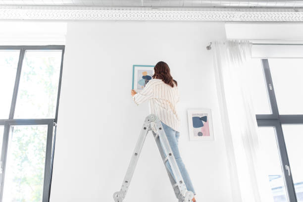 istock woman on ladder decorating home with art 1401530060