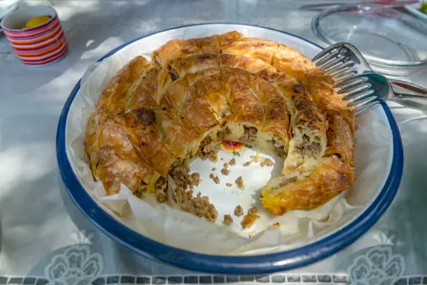 Minced meat in savory pastry on picnic table.