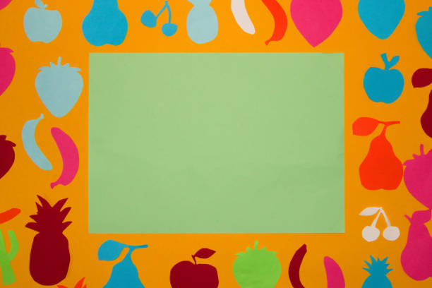 pastel green blank paper surrounded by orange background with colorful paper fruit, creative concept
