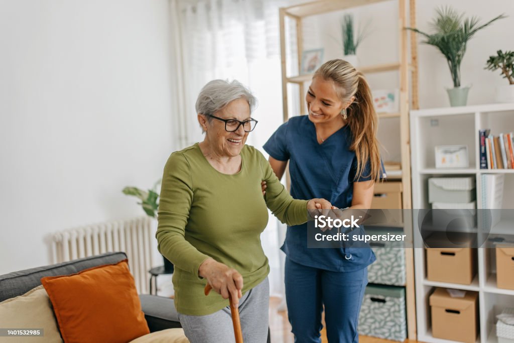 Step by step Female caregiver helping and supporting senior patient to walk at home, senior women is standing and holding walking cane Senior Adult Stock Photo