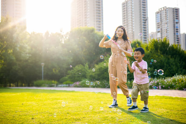 istock Mother and little son playing soap bubbles outdoor 1401534694