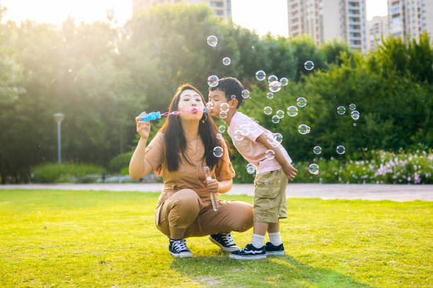 istock Mother and little son blowing soap bubbles outdoor 1401535698