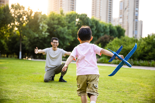 kids with father playing with toy planes in park