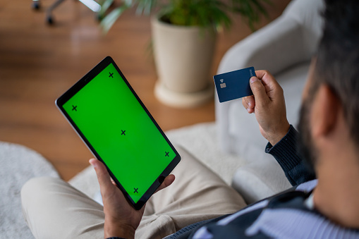 Man shopping online using digital tablet - green screen