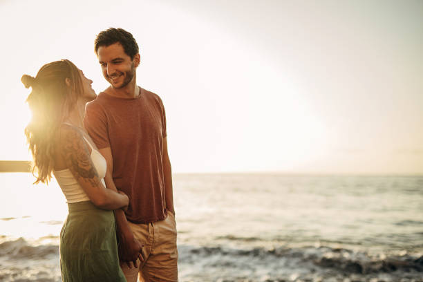 istock Young couple walking on the beach and enjoying sunset 1401538742