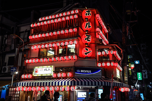 Osaka, Japan - January 11, 2020: Bright and Illuminated Red Building with Traditional Japanese Street Lights in Night Osaka