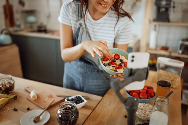 Beautiful cheerful woman vlogging from her domestic kitchen